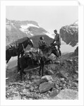 Couple man woman wearing riding gear jodhpurs boots spurs sitting standing on large rock by two horses by Anonymous
