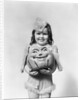 Happy smiling little girl in costume holding a papier-mache pumpkin head by Anonymous