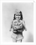 Happy smiling little girl in costume holding a papier-mache pumpkin head by Anonymous