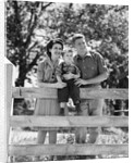 Smiling happy family mother father toddler boy portrait by farm fence by Anonymous