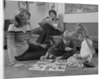 Family mother kids playing board game living room floor father reading newspaper by Anonymous