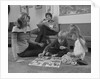 Family mother kids playing board game living room floor father reading newspaper by Anonymous