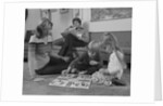 Family mother kids playing board game living room floor father reading newspaper by Anonymous