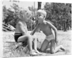 Blonde boy girl wearing bathing suits blowing on a pinwheel toy summer by Anonymous