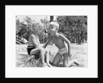 Blonde boy girl wearing bathing suits blowing on a pinwheel toy summer by Anonymous