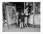 Mother and 2 children buying tickets to movie matinee boy wearing cowboy costume by Anonymous