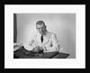 Portrait male doctor sitting at desk serious expression by Anonymous