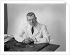 Portrait male doctor sitting at desk serious expression by Anonymous