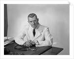 Portrait male doctor sitting at desk serious expression by Anonymous