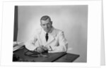 Portrait male doctor sitting at desk serious expression by Anonymous