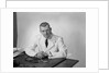 Portrait male doctor sitting at desk serious expression by Anonymous