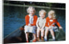 Boy and two girls in red sweaters sitting in back of rowboat by Anonymous