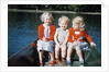 Boy and two girls in red sweaters sitting in back of rowboat by Anonymous