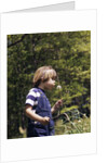 Boy wearing bib overalls blowing on dandelion head by Anonymous