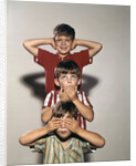 Boys posing as three wise monkeys see no evil hear no evil speak no evil by Corbis