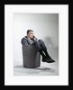 Sad man in business suit sitting in trash garbage can by Anonymous