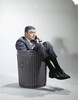 Sad man in business suit sitting in trash garbage can by Anonymous