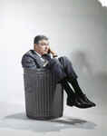 Sad man in business suit sitting in trash garbage can by Anonymous