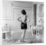 Back view of woman in bathroom fastening black bra by Anonymous