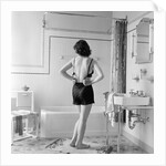 Back view of woman in bathroom fastening black bra by Anonymous