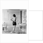 Back view of woman in bathroom fastening black bra by Anonymous