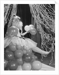 Woman dressed in harlequin costume sitting on stack of balloons by Anonymous