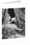 Woman dressed in harlequin costume sitting on stack of balloons by Anonymous