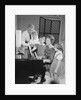 Family standing around piano singing by Anonymous