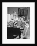 Family standing around piano singing by Anonymous