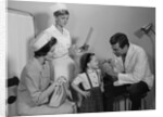 Mother sitting watching man pediatric doctor woman nurse checking on smiling little girl patient by Anonymous
