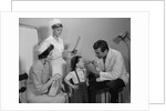 Mother sitting watching man pediatric doctor woman nurse checking on smiling little girl patient by Anonymous