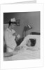 Woman nurse checking pulse taking temperature on little girl patient in hospital bed by Anonymous