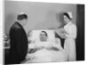 Man doctor woman nurse talking with male patient lying in hospital bed by Anonymous