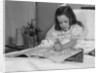 Little girl patient in hospital bed writing in coloring book by Anonymous