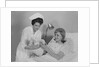 Woman nurse giving baby to smiling mother patient sitting in hospital bed by Anonymous
