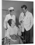 Man doctor woman nurse talking to smiling female patient sitting in hospital wheelchair by Anonymous