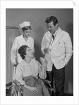 Man doctor woman nurse talking to smiling female patient sitting in hospital wheelchair by Anonymous