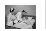 Doctor and nurse checking on elderly male patient in hospital bed by Anonymous