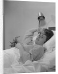 Ailing woman patient lying in hospital bed hand pressed to forehead by Anonymous