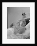 Ailing woman patient lying in hospital bed hand pressed to forehead by Anonymous