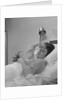 Ailing woman patient lying in hospital bed hand pressed to forehead by Anonymous