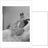Ailing woman patient lying in hospital bed hand pressed to forehead by Anonymous