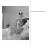 Ailing woman patient lying in hospital bed hand pressed to forehead by Anonymous