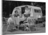 Family camping eating meal beside rv camper by Anonymous