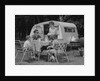 Family camping eating meal beside rv camper by Anonymous