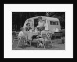 Family camping eating meal beside rv camper by Anonymous