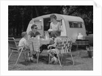 Family camping eating meal beside rv camper by Anonymous