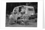 Family camping eating meal beside rv camper by Anonymous