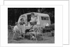 Family camping eating meal beside rv camper by Anonymous