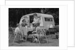 Family camping eating meal beside rv camper by Anonymous